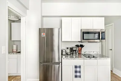 a kitchen with white cabinets and a stainless steel refrigerator at 73-406 New 1BR 1Bth UWS Doorman Gym in New York