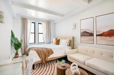 a white bedroom with a bed and a couch at 73-1111 New Studio UWS Doorman Gym in New York