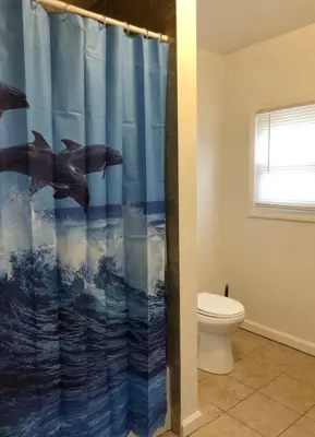 a bathroom with a dolphin shower curtain with a toilet at Private apartment with 3 bedrooms and 1 bathroom near Newark International Airport EWR and New York City, MetLife Stadium FIFA World Cup 20 minutes away in Newark