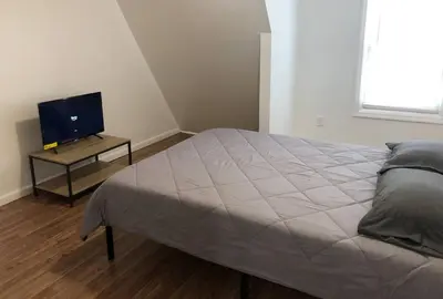 a bedroom with a bed and a television on a table at Private apartment with 3 bedrooms and 1 bathroom near Newark International Airport EWR and New York City, MetLife Stadium FIFA World Cup 20 minutes away in Newark