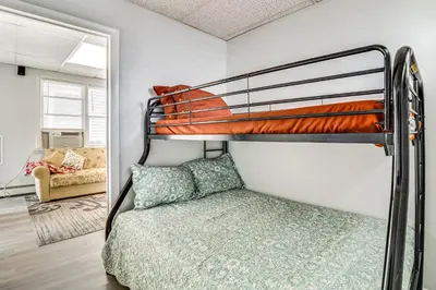 a bedroom with a bunk bed and a couch at Cozy Keansburg Cottage Walk to Beach and Boardwalk! in Keansburg