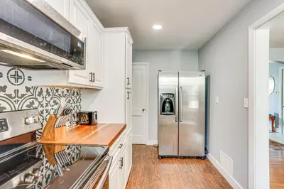 a kitchen with white cabinets and a stainless steel refrigerator at 10 Mi to Hersheypark Updated Family Retreat! in Annville