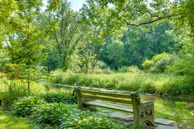 a park bench sitting in front of a pond at 10 Mi to Hersheypark Updated Family Retreat! in Annville
