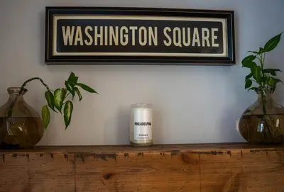 a candle sitting on a wooden shelf under a sign at Historic Family 3BR Trinity in the Heart of Philly in Philadelphia
