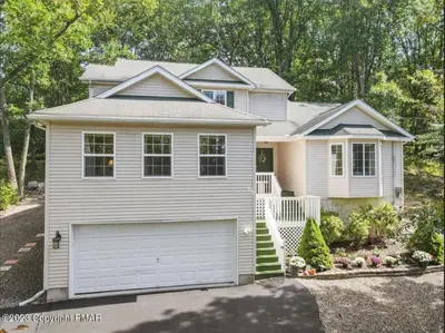 a white house with a garage in front of it at Charming, Restful Getaway in Bushkill