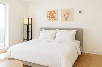 a white bedroom with a large bed with white sheets at Luxury Stay for NYC visit Jersey City 7 Min Walk NYC Train Station in Jersey City