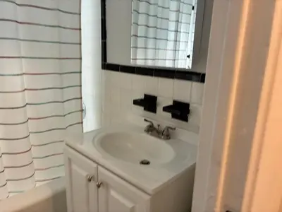 a white bathroom with a sink and a mirror at Chill In The Village in New York