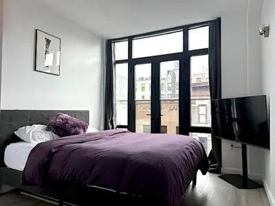 a bedroom with a bed and a large window at Huge Modern 2 bedroom in Little Italy in New York