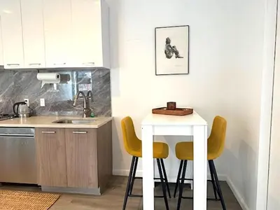a kitchen with a table and two yellow chairs at Huge Modern 2 bedroom in Little Italy in New York