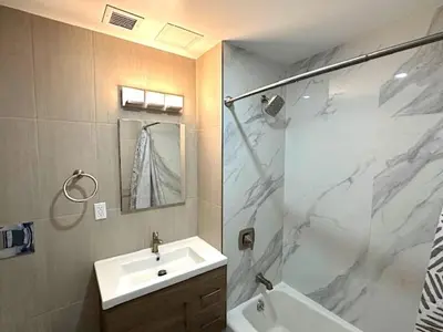 a bathroom with a sink and a shower with a mirror at Huge Modern 2 bedroom in Little Italy in New York