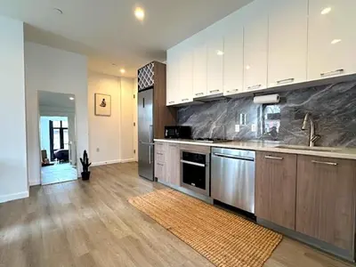 a large kitchen with stainless steel appliances and wooden floors at Huge Modern 2 bedroom in Little Italy in New York