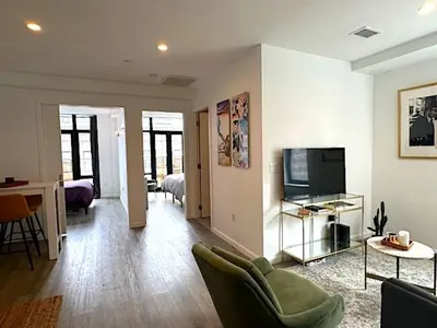 a living room with a couch and a television at Huge Modern 2 bedroom in Little Italy in New York