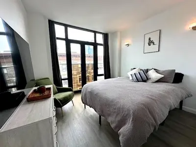 a bedroom with a bed and a large window at Huge Modern 2 bedroom in Little Italy in New York