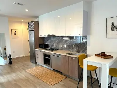 a kitchen with stainless steel appliances and a table at Huge Modern 2 bedroom in Little Italy in New York