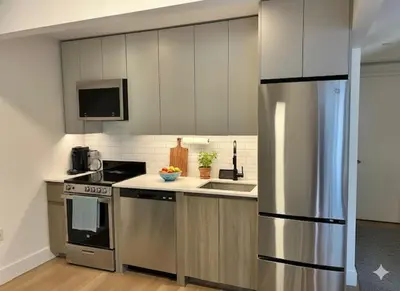 a kitchen with stainless steel appliances and white cabinets at Luxury in Little Italy 2 Bedroom Private Balcony in New York