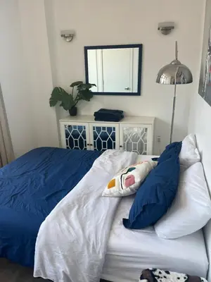 a bed with blue and white sheets and a mirror at Luxury in Little Italy 2 Bedroom Private Balcony in New York