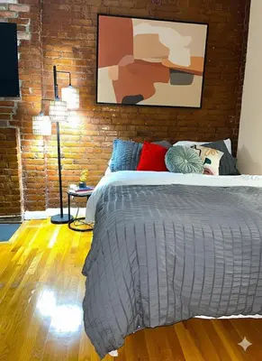 a bedroom with a bed and a brick wall at Beauty in the Heart of the Village in New York