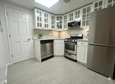 a kitchen with white cabinets and a stove at Beauty in the Heart of the Village in New York