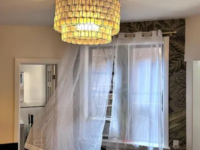 a chandelier and a window with a curtain at West Village Lush Green in New York
