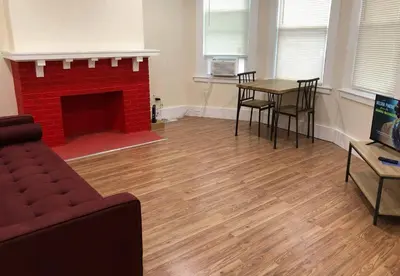 a living room with a red brick fireplace and a table at Spacious and private apartment with 3 bedrooms and 1 bathroom near Newark International Airport EWR and New York City, MetLife Stadium FIFA World Cup 20 minutes away in Newark