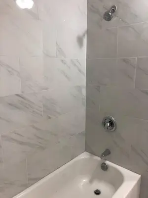 a white bathroom with a tub and a shower at Spacious and private apartment with 3 bedrooms and 1 bathroom near Newark International Airport EWR and New York City, MetLife Stadium FIFA World Cup 20 minutes away in Newark