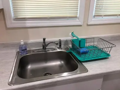a kitchen sink with a dish drying rack next to it at Spacious and private apartment with 3 bedrooms and 1 bathroom near Newark International Airport EWR and New York City, MetLife Stadium FIFA World Cup 20 minutes away in Newark