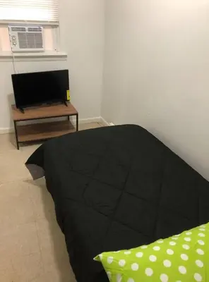 a bedroom with a black bed and a television at Private 3 bedroom and 1 bathroom house, direct NYC Manhattan train a 15 minute walk away, MetLife Stadium FIFA World Cup 35 minutes away in Perth Amboy
