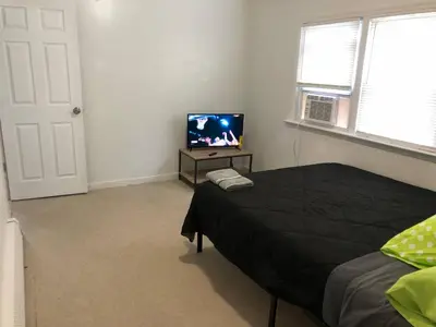 a bedroom with a bed and a flat screen tv at Private 3 bedroom and 1 bathroom house, direct NYC Manhattan train a 15 minute walk away, MetLife Stadium FIFA World Cup 35 minutes away in Perth Amboy