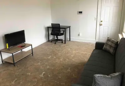 a living room with a couch and a table and a television at Spacious and bright 2-bedroom apartment with 1-bathroom and private street entrance, MetLife Stadium FIFA World Cup 25 minutes away in Paterson