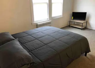 a bedroom with a large bed and a television at Spacious and bright 2-bedroom apartment with 1-bathroom and private street entrance, MetLife Stadium FIFA World Cup 25 minutes away in Paterson
