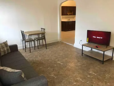 a living room with a couch and a table and a tv at Spacious and bright 2-bedroom apartment with 1-bathroom and private street entrance, MetLife Stadium FIFA World Cup 25 minutes away in Paterson