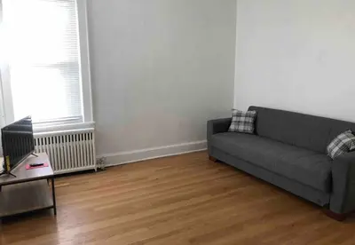 a living room with a couch and a wooden floor at Spacious 2-bedroom apartment with 1-bathroom and private street entrance, MetLife Stadium FIFA World Cup 25 minutes away in Paterson