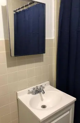 a bathroom with a sink and a blue shower curtain at Private apartment with 1 bedroom and 1 bathroom, MetLife Stadium FIFA World Cup 25 minutes away in Paterson