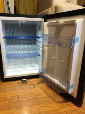 an empty refrigerator with its door open on a wooden floor at Private 1-bedroom RV, direct bus to NYC Manhattan only 2 blocks away, MetLife Stadium FIFA World Cup 25 minutes away in Linden