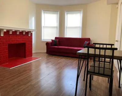 a living room with a red couch and a fireplace at Large and private 3 bedroom and 1 bathroom apartment near Newark International Airport EWR and New York City, MetLife Stadium FIFA World Cup 20 minutes away in Newark