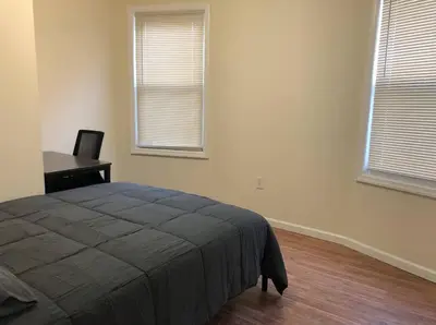 a bedroom with a bed and a desk and two windows at Large and private 3 bedroom and 1 bathroom apartment near Newark International Airport EWR and New York City, MetLife Stadium FIFA World Cup 20 minutes away in Newark