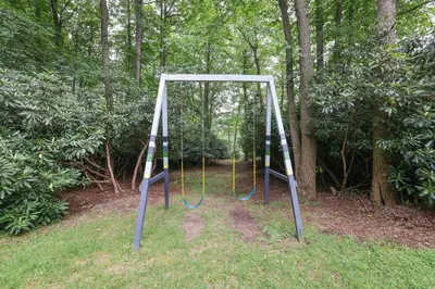 a swing set in a park with trees at Green Acres Nature Escape in Long Pond