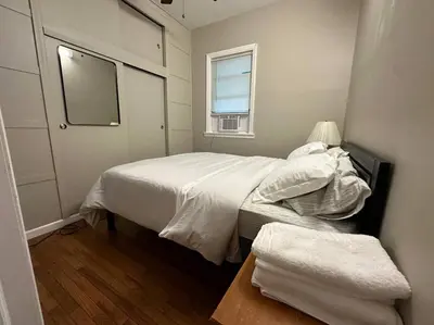 a small bedroom with a bed and a window at Stunning 4BR home close to NYC in Teaneck