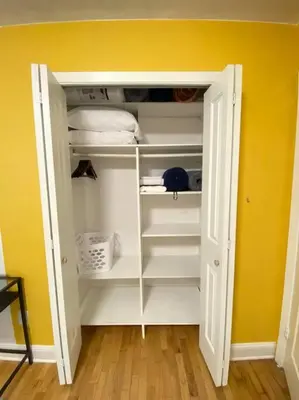 a closet with white shelves and a yellow wall at Live in NYC -20 Mins to Rockefeller, MoMA & World in Jersey City