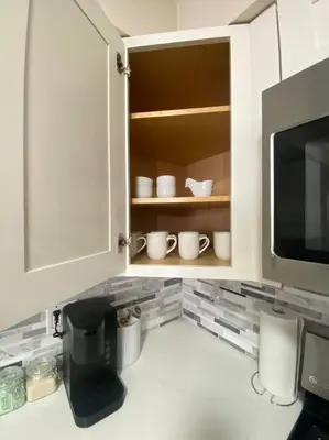 a kitchen with a cupboard with cups and a microwave at Live in NYC -20 Mins to Rockefeller, MoMA & World in Jersey City