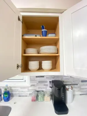 a kitchen cabinet with plates and dishes in it at Live in NYC -20 Mins to Rockefeller, MoMA & World in Jersey City