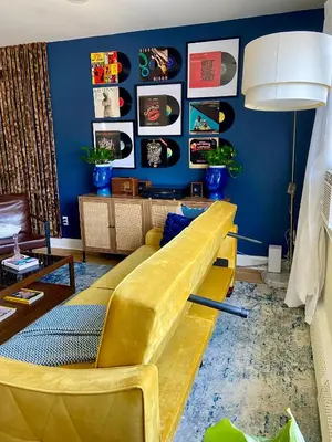 a yellow couch in a living room with a blue wall at Live in NYC -20 Mins to Rockefeller, MoMA & World in Jersey City