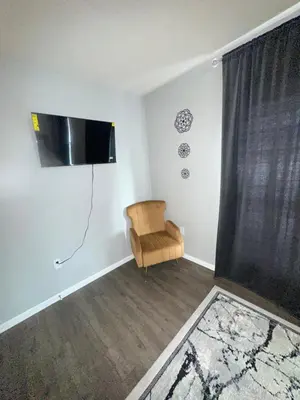 a living room with a chair and a flat screen tv at Elegant Apt by EWR & PennStation in Newark
