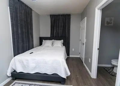 a bedroom with a bed with white sheets and a toilet at Elegant Apt by EWR & PennStation in Newark