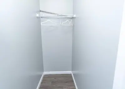 a closet with white walls and a shelf with hangers at Elegant Apt by EWR & PennStation in Newark