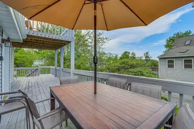 a wooden table with an umbrella on a balcony at Spacious Family Retreat Pocono Home with Deck in Albrightsville