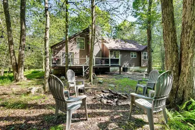 a group of chairs sitting in front of a house at Cozy Wooded Retreat Big Bass Lake Home in Lehigh