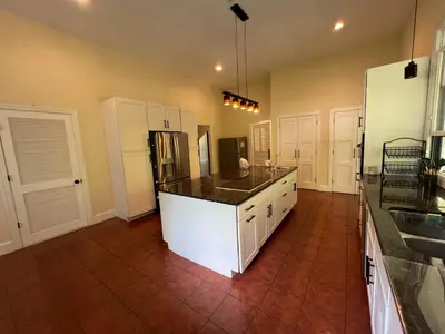a large kitchen with a counter and a refrigerator at Beautiful River front home with private pool in Phillipsburg
