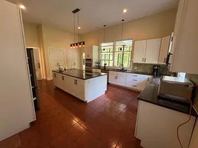 a large kitchen with white cabinets and a tile floor at Beautiful River front home with private pool in Phillipsburg