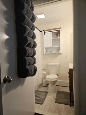 a bathroom with a toilet with black towels on the door at Cozy & Modern 3-Bed Retreat - 8 Mins to Bridge St in Phoenixville